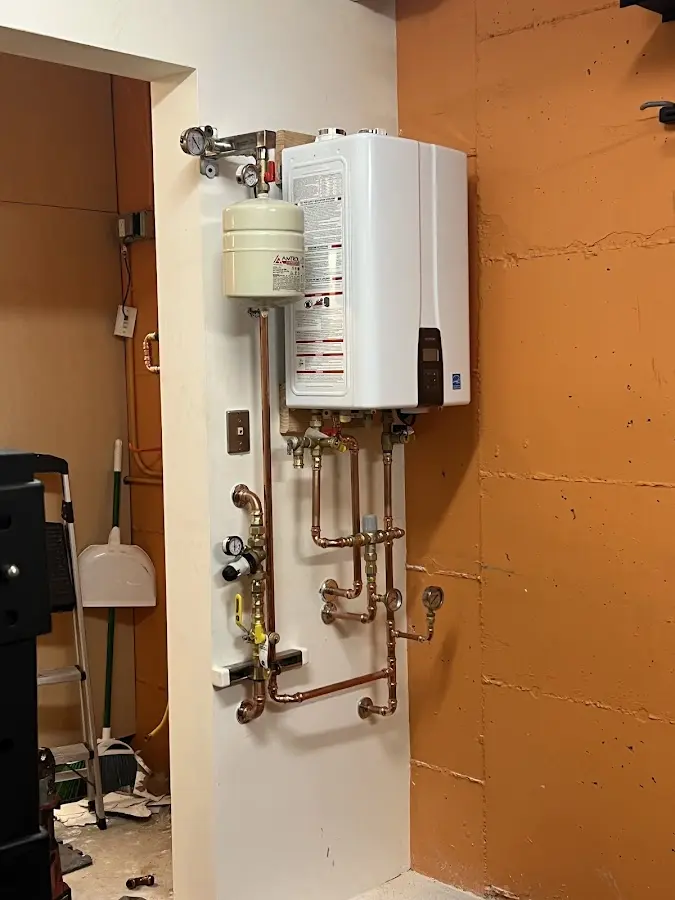 Plumbing technician inspecting water heater connections in St. Ann